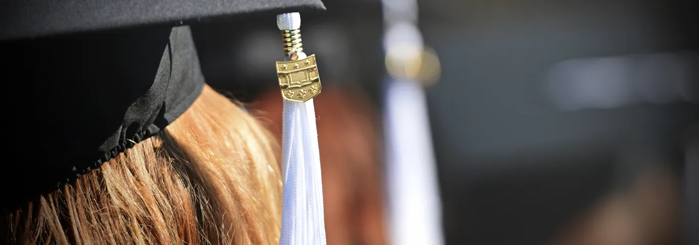 a close photo of a graduation tassle hanging from a cap